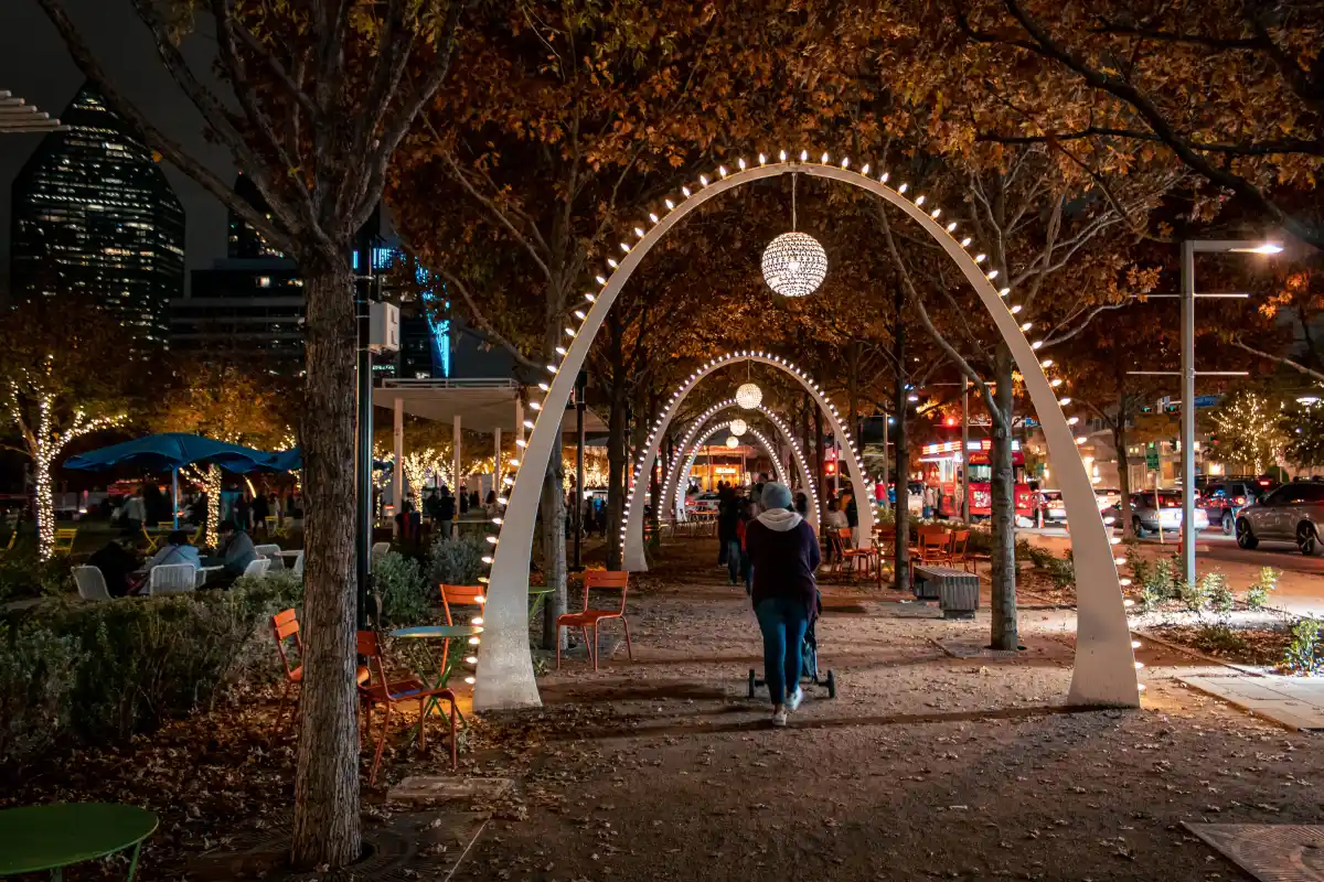 Lit arches over the walkway at Klyde Warren Park in the evening